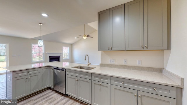 kitchen featuring open floor plan, a peninsula, a sink, gray cabinets, and stainless steel dishwasher