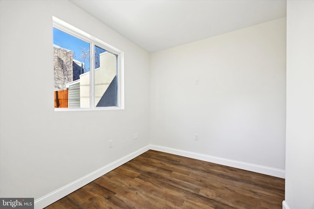 unfurnished room with dark wood-style floors and baseboards