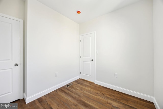 unfurnished room with dark wood-style floors, baseboards, and visible vents