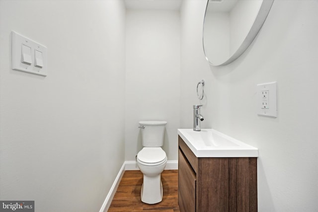 bathroom featuring vanity, wood finished floors, toilet, and baseboards