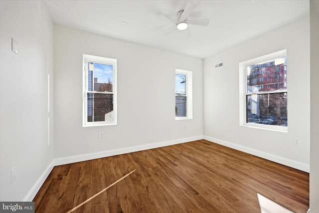 unfurnished room featuring visible vents, baseboards, ceiling fan, and wood finished floors