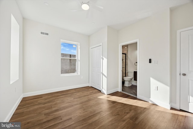 unfurnished bedroom featuring dark wood-style floors, visible vents, connected bathroom, and baseboards