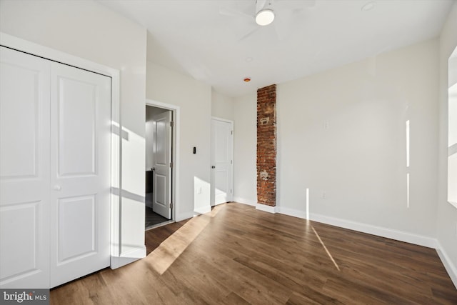 unfurnished bedroom with dark wood-style flooring, a ceiling fan, and baseboards