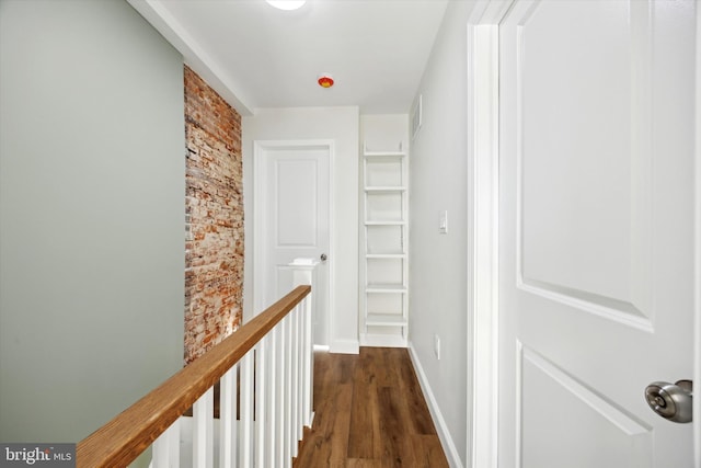 hallway with visible vents, dark wood-style floors, an upstairs landing, and baseboards