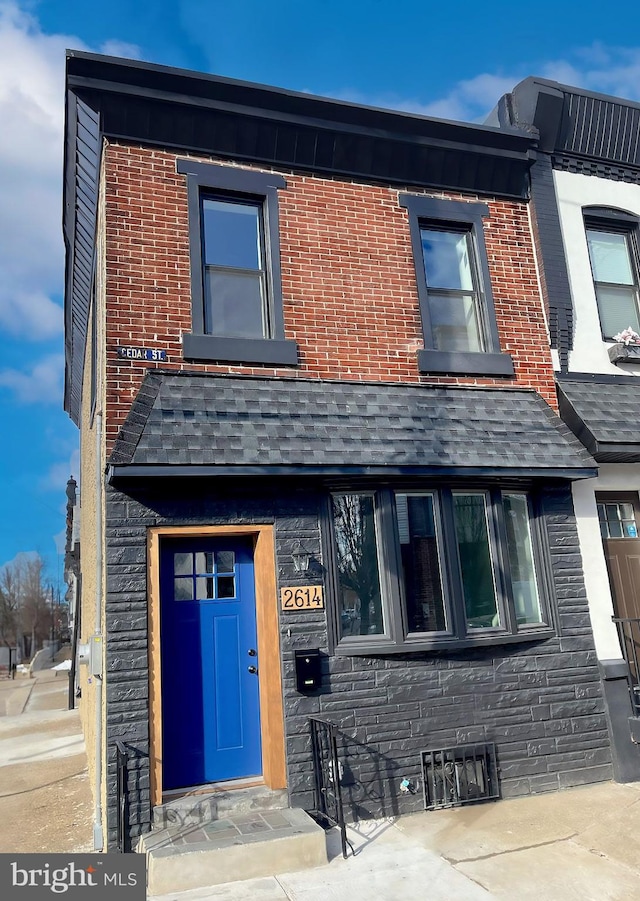 townhome / multi-family property with entry steps, stone siding, and brick siding