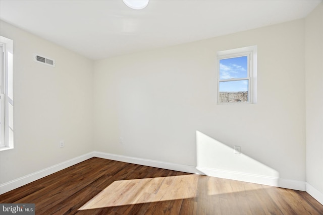 empty room featuring baseboards, visible vents, and wood finished floors