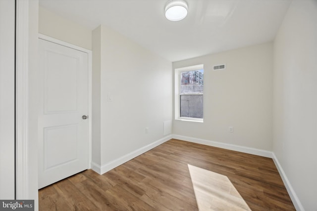 unfurnished room featuring visible vents, baseboards, and wood finished floors