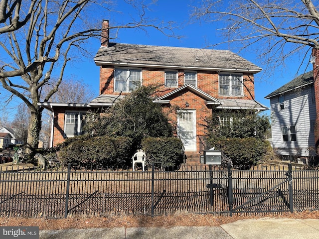 view of front of home featuring a fenced front yard, brick siding, and a chimney