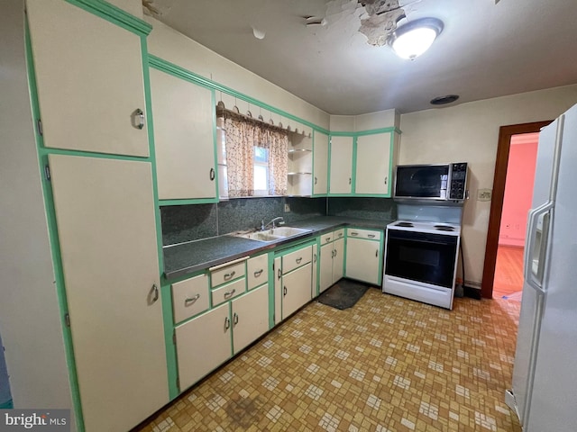 kitchen with electric stove, open shelves, dark countertops, freestanding refrigerator, and a sink