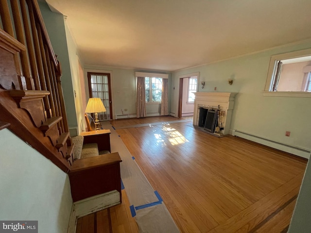 unfurnished living room featuring light wood finished floors, stairway, ornamental molding, baseboard heating, and a fireplace