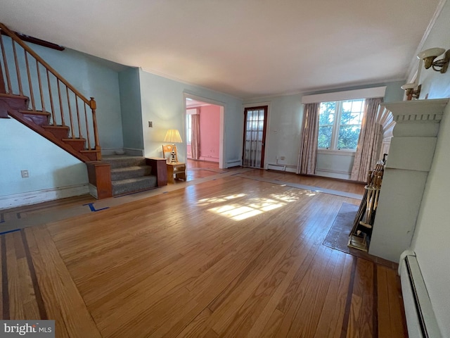 unfurnished living room with stairs, baseboard heating, and wood-type flooring