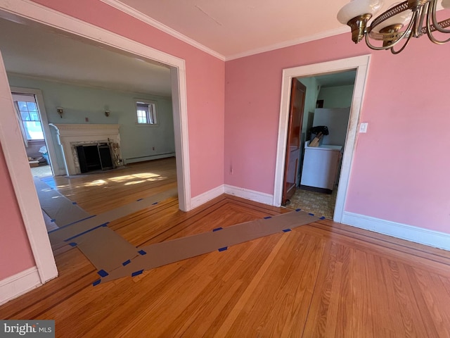 unfurnished dining area featuring crown molding, a baseboard heating unit, a fireplace with flush hearth, wood finished floors, and baseboards