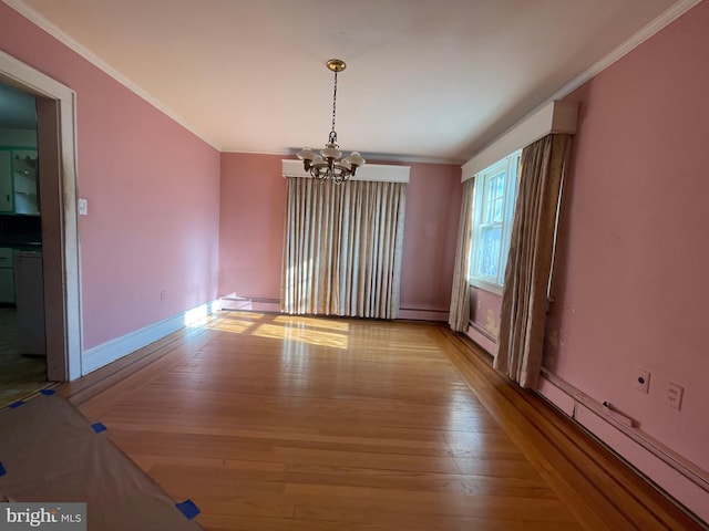 spare room featuring a notable chandelier, light wood-style floors, and crown molding