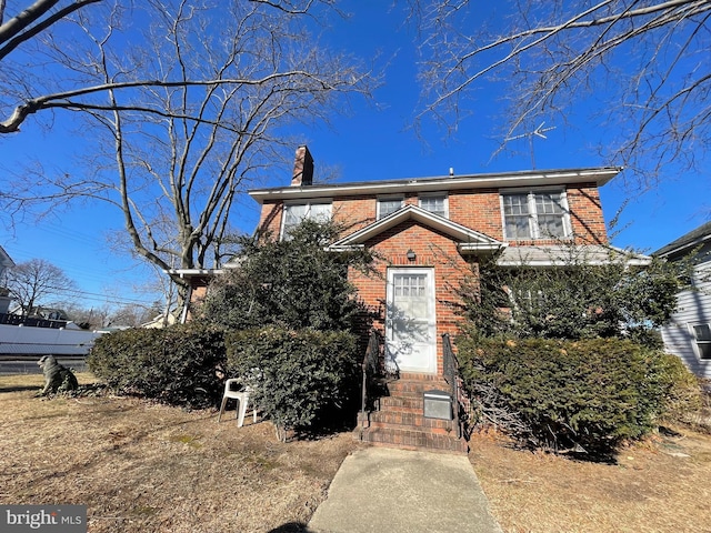 view of front of property with entry steps, a chimney, and brick siding