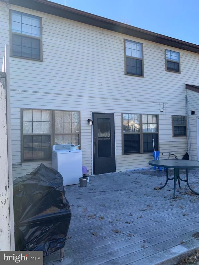 rear view of property featuring washer / dryer and a deck