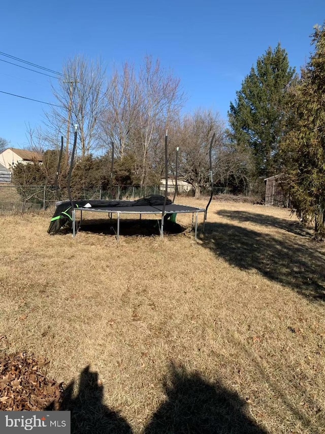 view of yard with a trampoline and fence