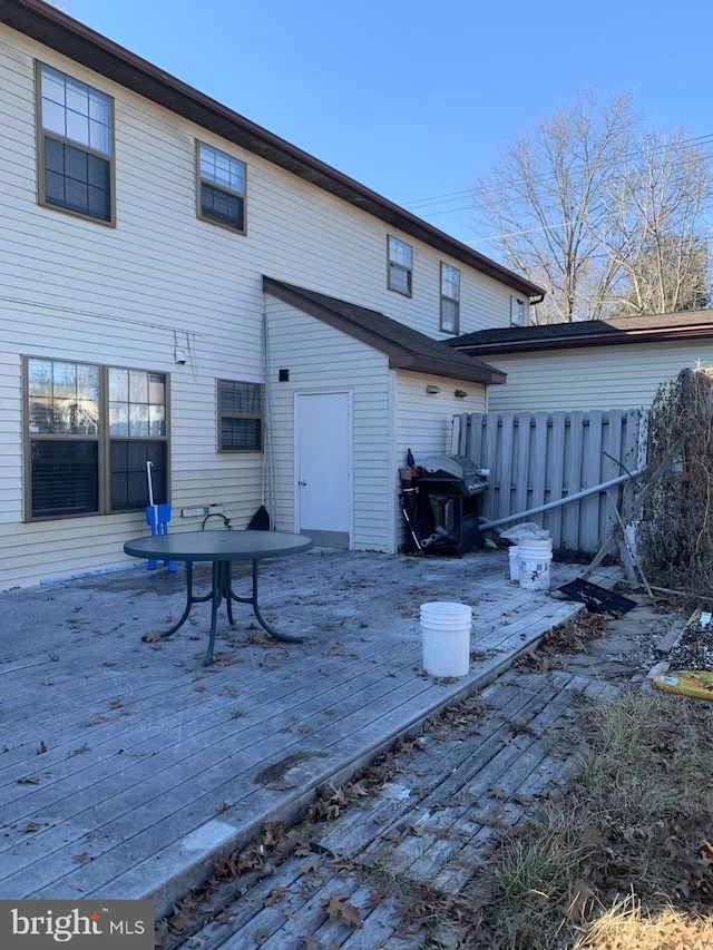 rear view of property featuring fence and a wooden deck