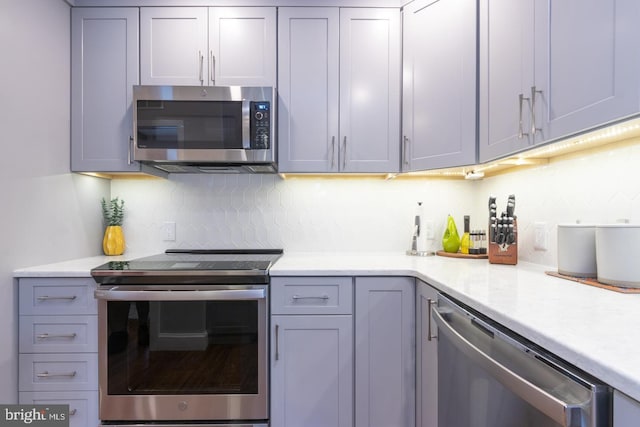 kitchen featuring appliances with stainless steel finishes, decorative backsplash, and gray cabinetry