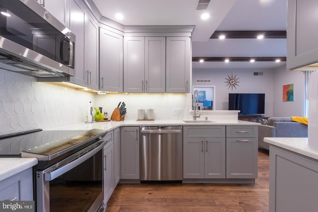 kitchen with a sink, gray cabinets, stainless steel appliances, and light countertops