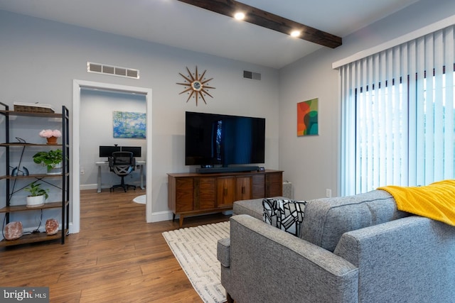 living area featuring baseboards, visible vents, beam ceiling, and wood finished floors