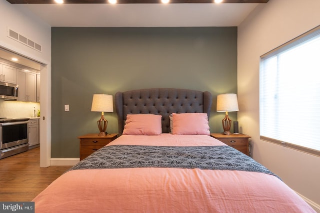 bedroom featuring baseboards, visible vents, light wood finished floors, and multiple windows