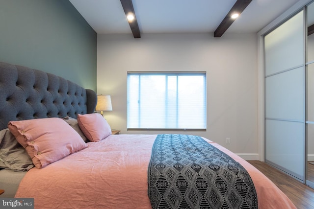 bedroom with beamed ceiling, baseboards, and wood finished floors