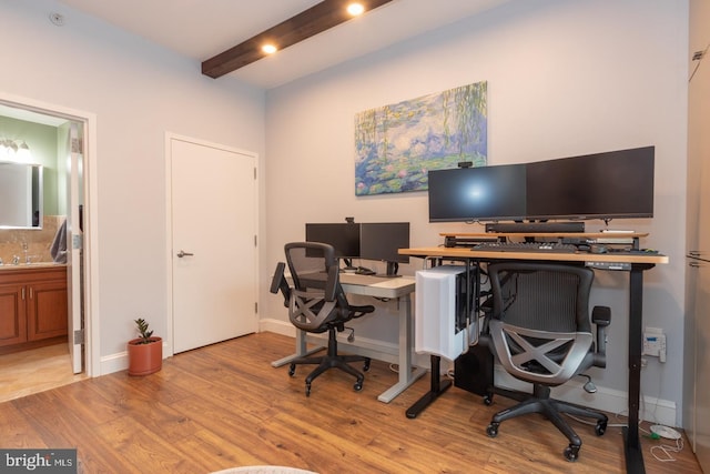 office space featuring light wood-style flooring, baseboards, and beamed ceiling