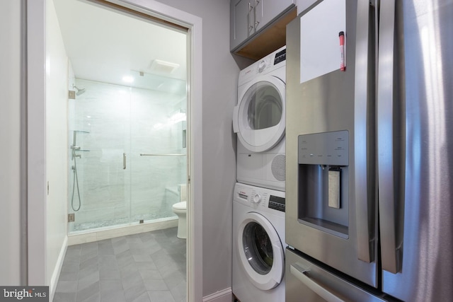 laundry room featuring stacked washer and clothes dryer, baseboards, and laundry area