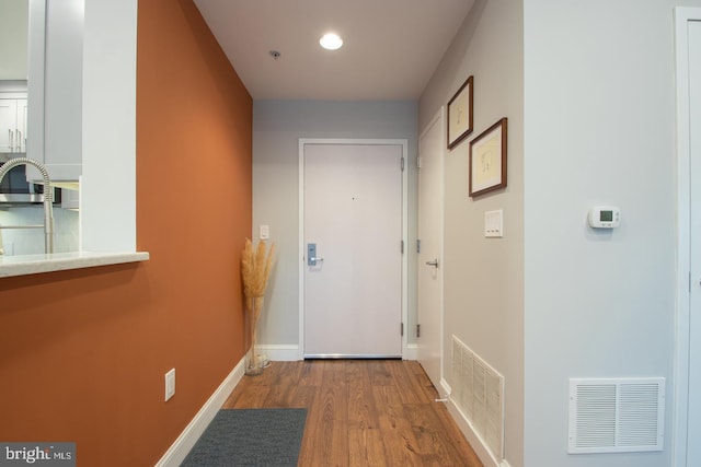 doorway with visible vents, baseboards, and wood finished floors