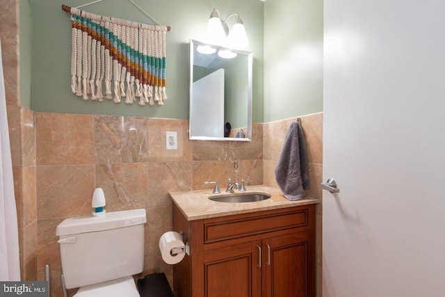 bathroom featuring vanity, toilet, and tile walls