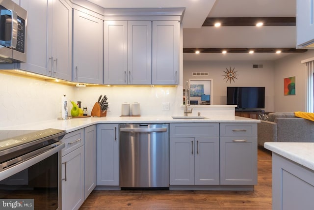 kitchen featuring appliances with stainless steel finishes, gray cabinets, a sink, and visible vents