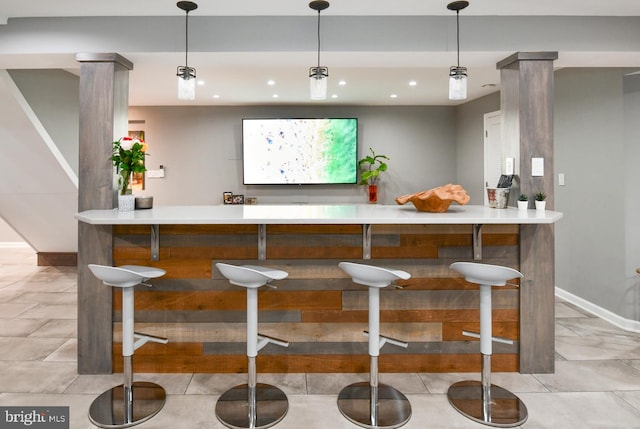 bar featuring hanging light fixtures, bar area, recessed lighting, and baseboards