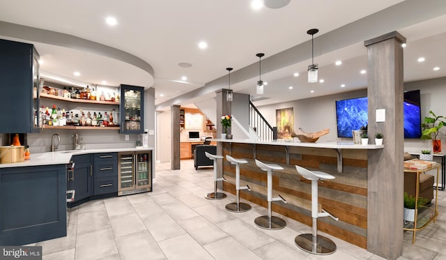 bar with wine cooler, pendant lighting, indoor wet bar, recessed lighting, and ornate columns