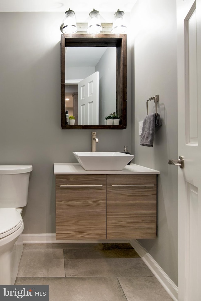 half bathroom with toilet, vanity, and baseboards