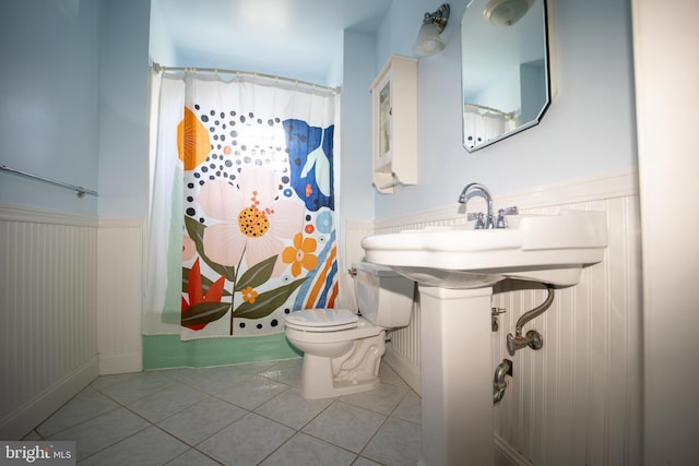 bathroom with a wainscoted wall, a shower with shower curtain, tile patterned flooring, and toilet