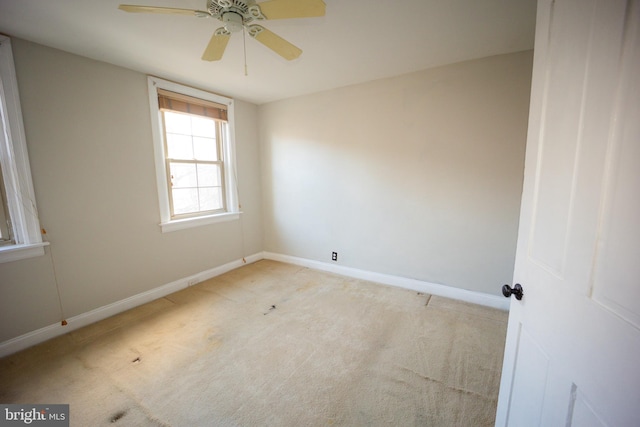 unfurnished room featuring light colored carpet, ceiling fan, and baseboards