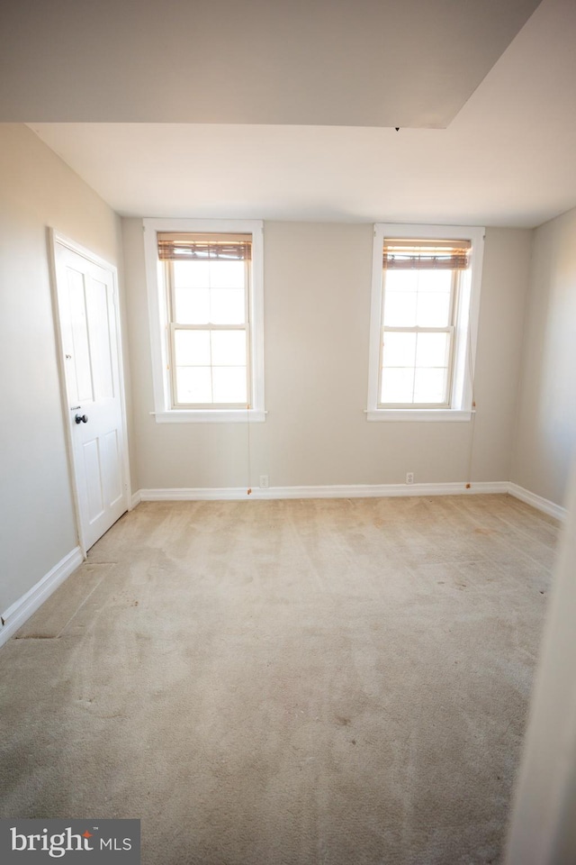 unfurnished room with light carpet, baseboards, and a wealth of natural light