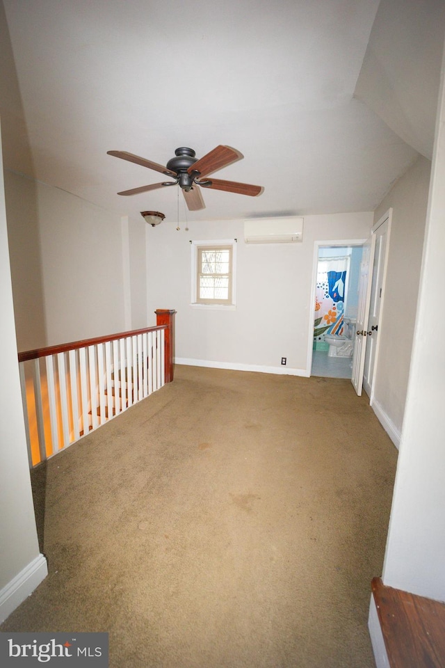 carpeted spare room featuring baseboards and an AC wall unit