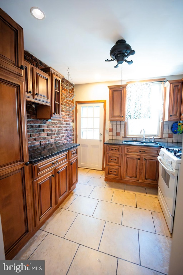 kitchen featuring glass insert cabinets, brown cabinets, a sink, and white gas stove