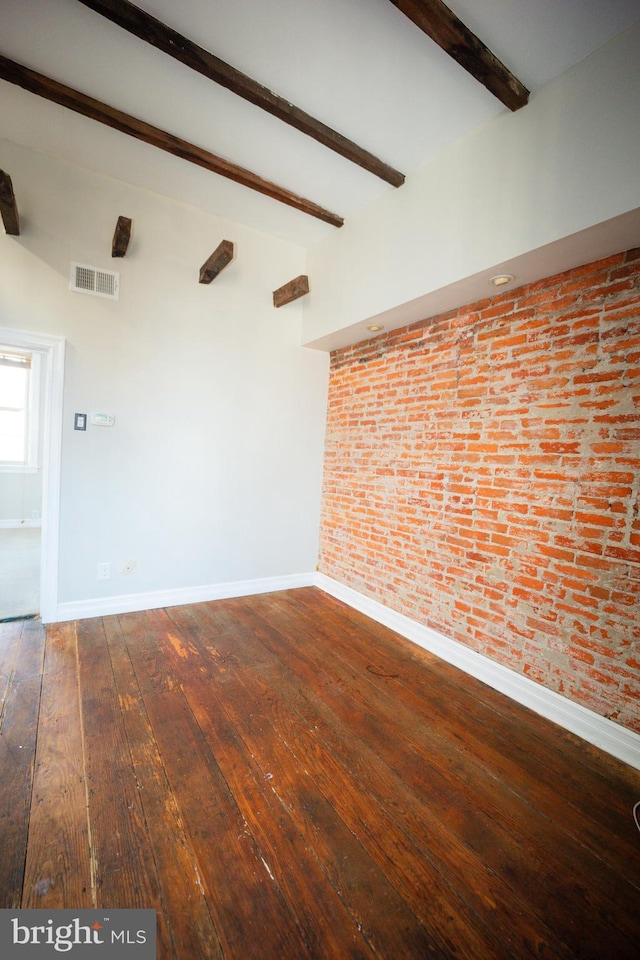 empty room featuring brick wall, visible vents, baseboards, beam ceiling, and dark wood finished floors