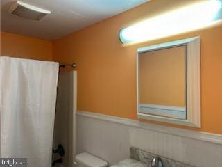 bathroom featuring a wainscoted wall and toilet