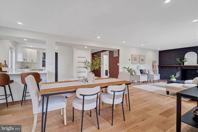 dining space featuring recessed lighting, a brick fireplace, visible vents, and light wood-style flooring