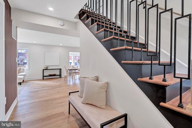 stairway with baseboards, plenty of natural light, wood finished floors, and recessed lighting