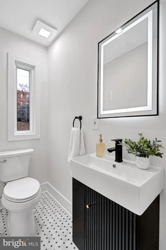 half bath with vanity, toilet, and baseboards