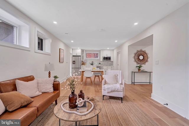 living room with light wood-type flooring, visible vents, baseboards, and recessed lighting