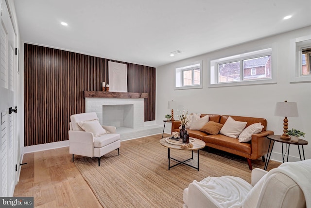 living area with recessed lighting, a fireplace, visible vents, baseboards, and light wood finished floors