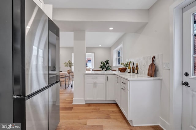 kitchen featuring white cabinets, light wood-style flooring, freestanding refrigerator, light countertops, and recessed lighting