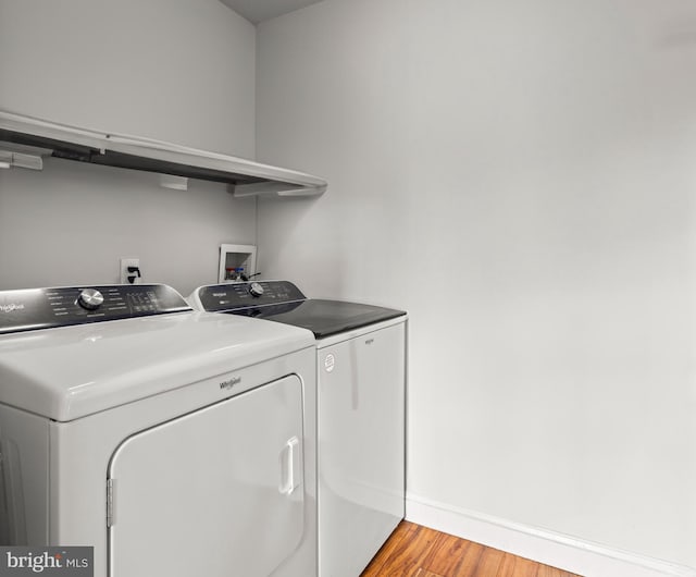 laundry area featuring laundry area, light wood-type flooring, washing machine and clothes dryer, and baseboards