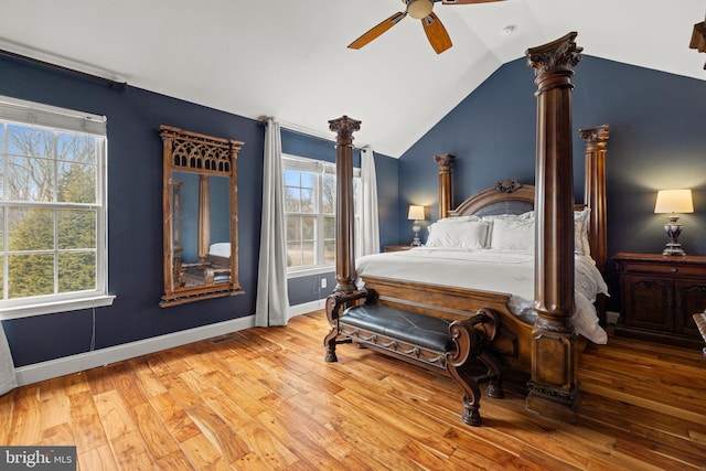 bedroom with baseboards, multiple windows, vaulted ceiling, and hardwood / wood-style floors