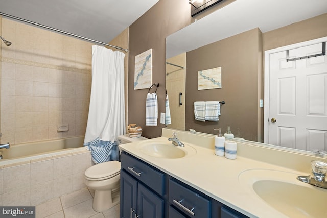 bathroom with tile patterned flooring, a sink, tiled shower / bath combo, and toilet